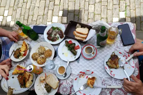 Pyszne albania jedzenie: mięso, gołąbki, placki i pieczywo na stole, obok piwo i kawa.