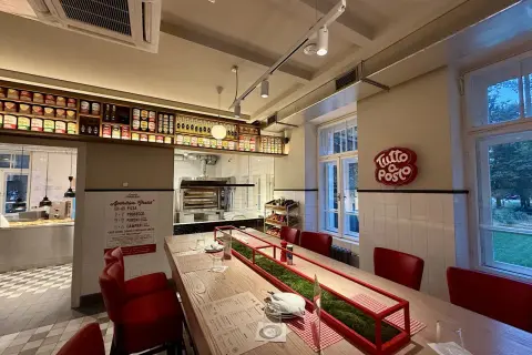 Wnętrze restauracji z długim stołem, czerwonymi krzesłami i piecem do pizzy. Otto Pompieri opinie pozytywne, warto odwiedzić!
