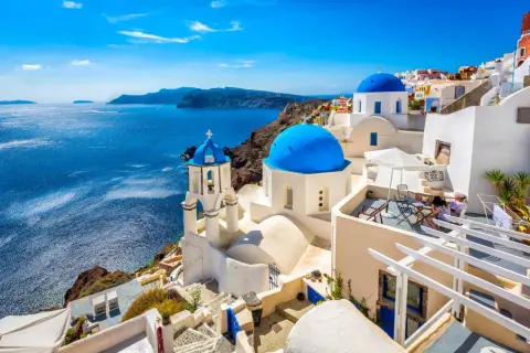 Białe domy z niebieskimi kopułami na greckich wyspach, Santorini, z widokiem na turkusowe morze.