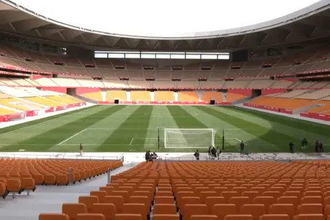 Pusta trybuna stadionu La Cartuja z pomarańczowymi siedzeniami i zieloną murawą.