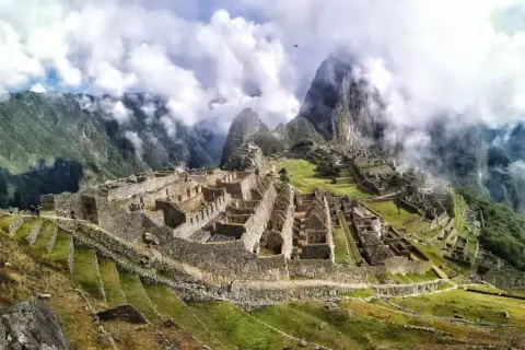 Niesamowita wycieczka do Machu Picchu. Ruiny Inków w chmurach, otoczone zielonymi tarasami i stromymi górami.