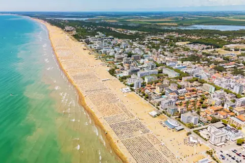 Słoneczna bibione plaża tętni życiem. Tysiące leżaków i parasoli tworzą barwny dywan, a turkusowe morze zaprasza do kąpieli.