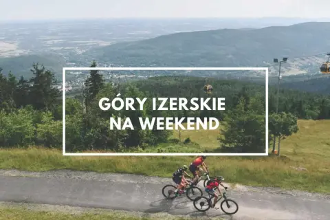 Góry Izerskie Polska: rowerzyści pędzą po górskiej drodze, w tle kolejka gondolowa i rozległy krajobraz.