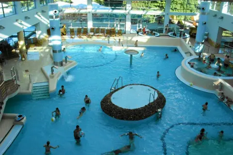 Wesoła atmosfera w aquaparku w Sopocie. Ludzie kąpią się w basenach, relaksują w jacuzzi. Wiele pozytywnych **aquapark sopot opinie** potwierdza, że to świetne miejsce na rodzinny wypoczynek.