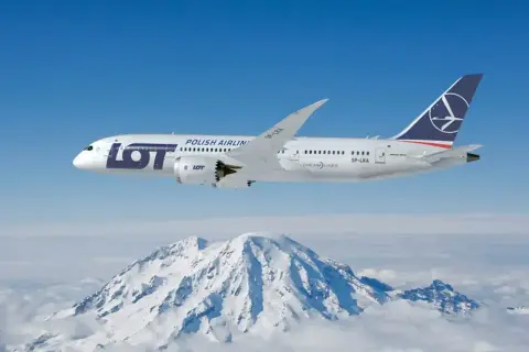 Samolot LOT Polish Airlines leci nad ośnieżonymi górami.