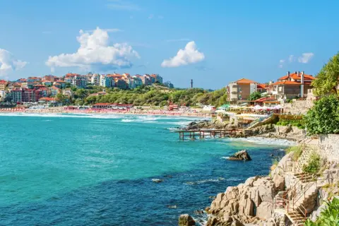 Słoneczne bułgaria plaże z turkusową wodą, kolorowymi budynkami na wzgórzu i kamiennymi schodami prowadzącymi do morza.