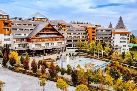 Hotel Gołębiewski w jesiennej odsłonie. Widać jego rozległą architekturę i otoczenie pełne kolorowych drzew.