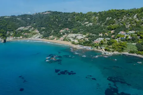 Widok na zatokę z piaszczystą plażą i zielonymi wzgórzami. To malownicza mysia wyspa Korfu, idealna na wakacje.