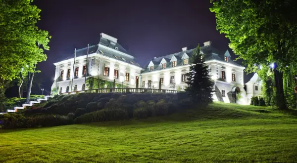 Elegancki pałac nocą, oświetlony blaskiem lamp, otoczony zielenią. Idealne miejsce na romantyczny wypad, jak w najlepszych hotelach dla dorosłych.