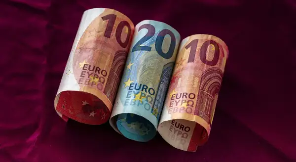 Dwa banknoty 10 euro i jeden 20 euro leżą na bordowym materiale. Łotwa waluta euro.