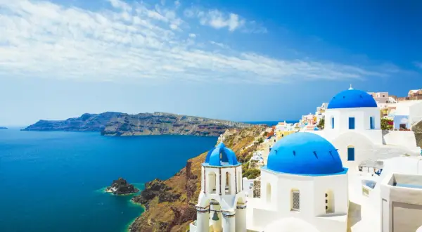 Santorini: białe domy, niebieskie kopuły kościołów i turkusowe morze. Idealne miejsce na tanie wakacje w Grecji.