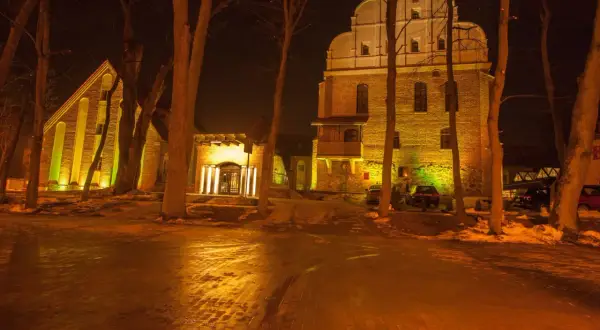 Nocą oświetlone budynki i drzewa tworzą magiczny klimat. To jedno z fajnych miejsc na wakacje w Polsce, które warto odkryć.