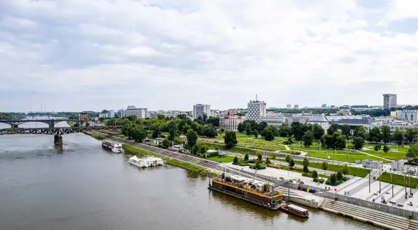 Widok na Wisłę i warszawskie Powiśle z nowoczesnymi bulwarami, mostem i zabudową miejską w tle.