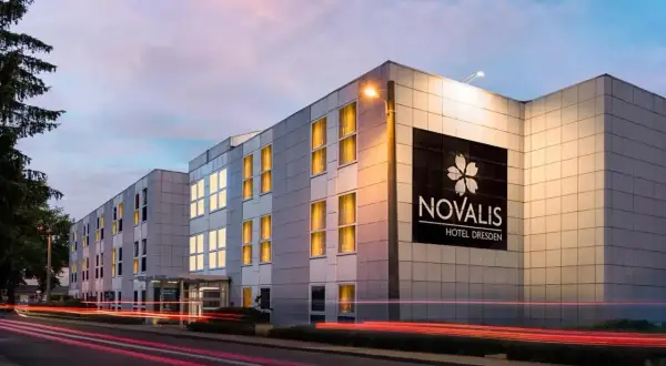 Novalis Hotel Dresden, z oświetlonymi oknami i neonowym znakiem, pokazuje, czym się różni hotel od motelu: oferuje więcej niż tylko nocleg.