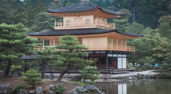 Złoty Pawilon Kinkaku-ji, cel mojej wycieczki do Japonii, odbija się w spokojnej tafli stawu.