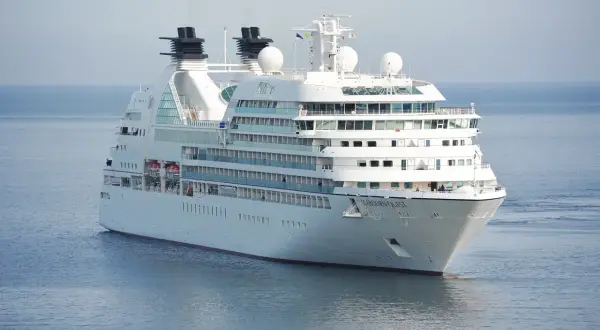 Biały statek wycieczkowy Seabourn Quest płynie po spokojnym, błękitnym morzu.