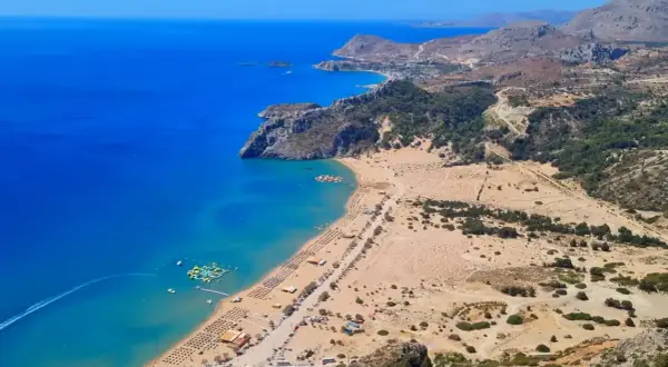 Widok na zatokę z piaszczystą plażą, leżakami i wodnym parkiem rozrywki. To jedno z rodos najpiękniejsze miejsca.