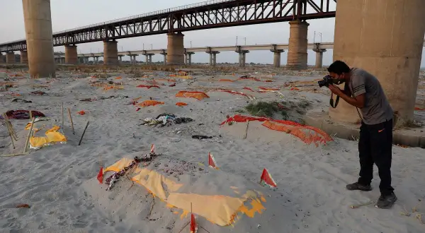 Brzeg rzeki Ganges, gdzie leżą przykryte materiałem ciała, tworzy widok przypominający cmentarzysko. Fotograf dokumentuje tę smutną rzeczywistość.