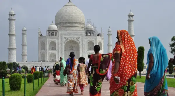 Kobiety w barwnych sari spacerują ścieżką ku Taj Mahal. Marzenie o podróży do Indii i uzyskaniu wizy do Indii staje się rzeczywistością.