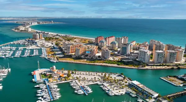 Widok na la manga hiszpania z licznymi jachtami w marinach i apartamentowcami nad turkusowym morzem.