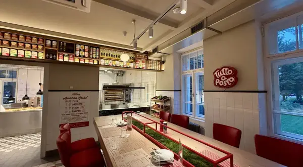Wnętrze restauracji z długim stołem, czerwonymi krzesłami i piecem do pizzy. Otto Pompieri opinie pozytywne, warto odwiedzić!