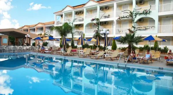 Basen i leżaki przy hotelu Admiral Tsilivi. Goście odpoczywają, a budynek hotelowy odbija się w krystalicznie czystej wodzie.