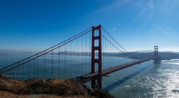 Ikoniczny most w San Francisco rozciąga się nad błękitną wodą, z panoramą miasta w oddali.