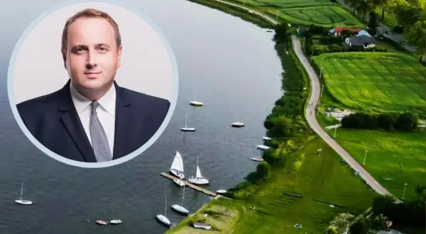 Portret mężczyzny w garniturze na tle malowniczego zalewu zemborzyckiego z żaglówkami.