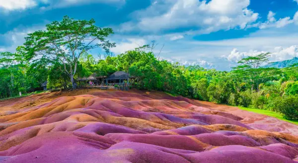Kolorowe wydmy na Mauritiusie, które warto zobaczyć. W tle bujna zieleń i chmury.