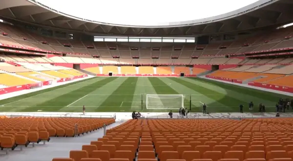 Pusta trybuna stadionu La Cartuja z pomarańczowymi siedzeniami i zieloną murawą.