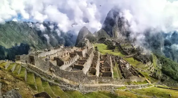 Niesamowita wycieczka do Machu Picchu. Ruiny Inków w chmurach, otoczone zielonymi tarasami i stromymi górami.