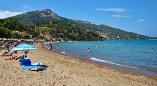 Idealna zakynthos pogoda czerwiec: słońce, plaża i kąpiel w turkusowym morzu. W tle zielone wzgórza.