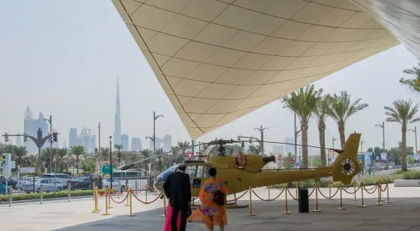 Luksusowe dubaj wczasy: ludzie podziwiają helikopter na tle drapaczy chmur.
