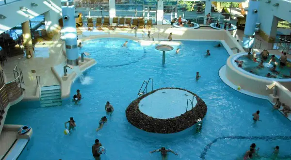 Wesoła atmosfera w aquaparku w Sopocie. Ludzie kąpią się w basenach, relaksują w jacuzzi. Wiele pozytywnych **aquapark sopot opinie** potwierdza, że to świetne miejsce na rodzinny wypoczynek.