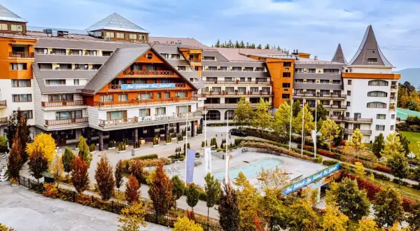 Hotel Gołębiewski w jesiennej odsłonie. Widać jego rozległą architekturę i otoczenie pełne kolorowych drzew.