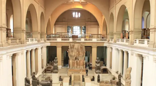 Wielka sala w muzeum w Kairze, pełna starożytnych posągów i artefaktów. Monumentalne rzeźby faraonów dominują w centrum.