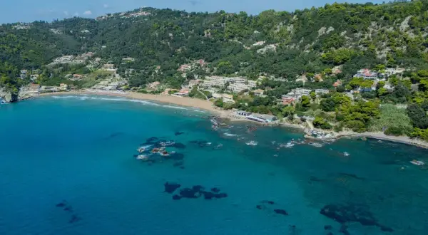 Widok na zatokę z piaszczystą plażą i zielonymi wzgórzami. To malownicza mysia wyspa Korfu, idealna na wakacje.