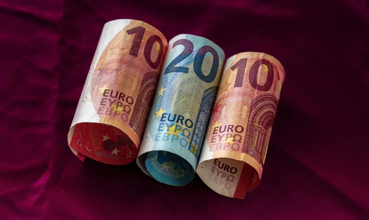 Dwa banknoty 10 euro i jeden 20 euro leżą na bordowym materiale. Łotwa waluta euro.