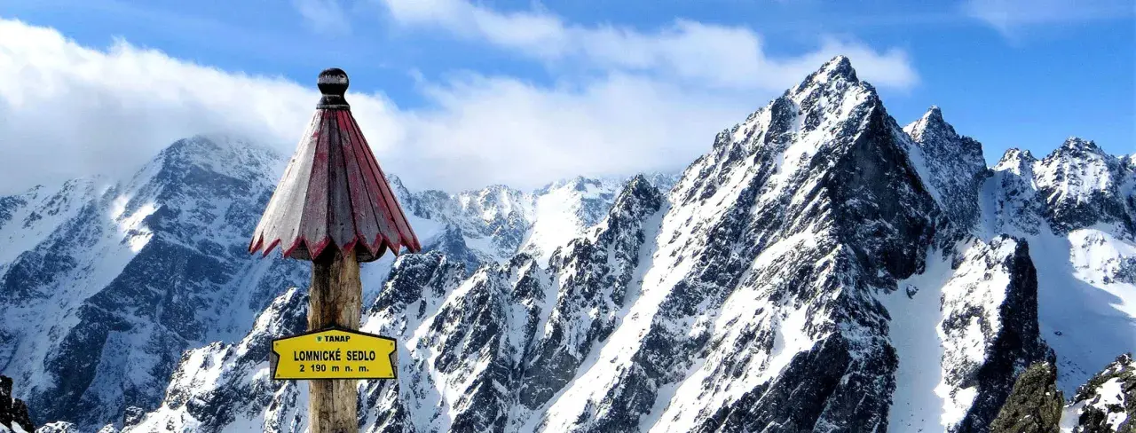 Słowacja góry: szczyt Łomnickie Sedlo (2190 m n.p.m.) w Tatrach Wysokich, pokryty śniegiem, z charakterystycznym drewnianym słupkiem i tabliczką.