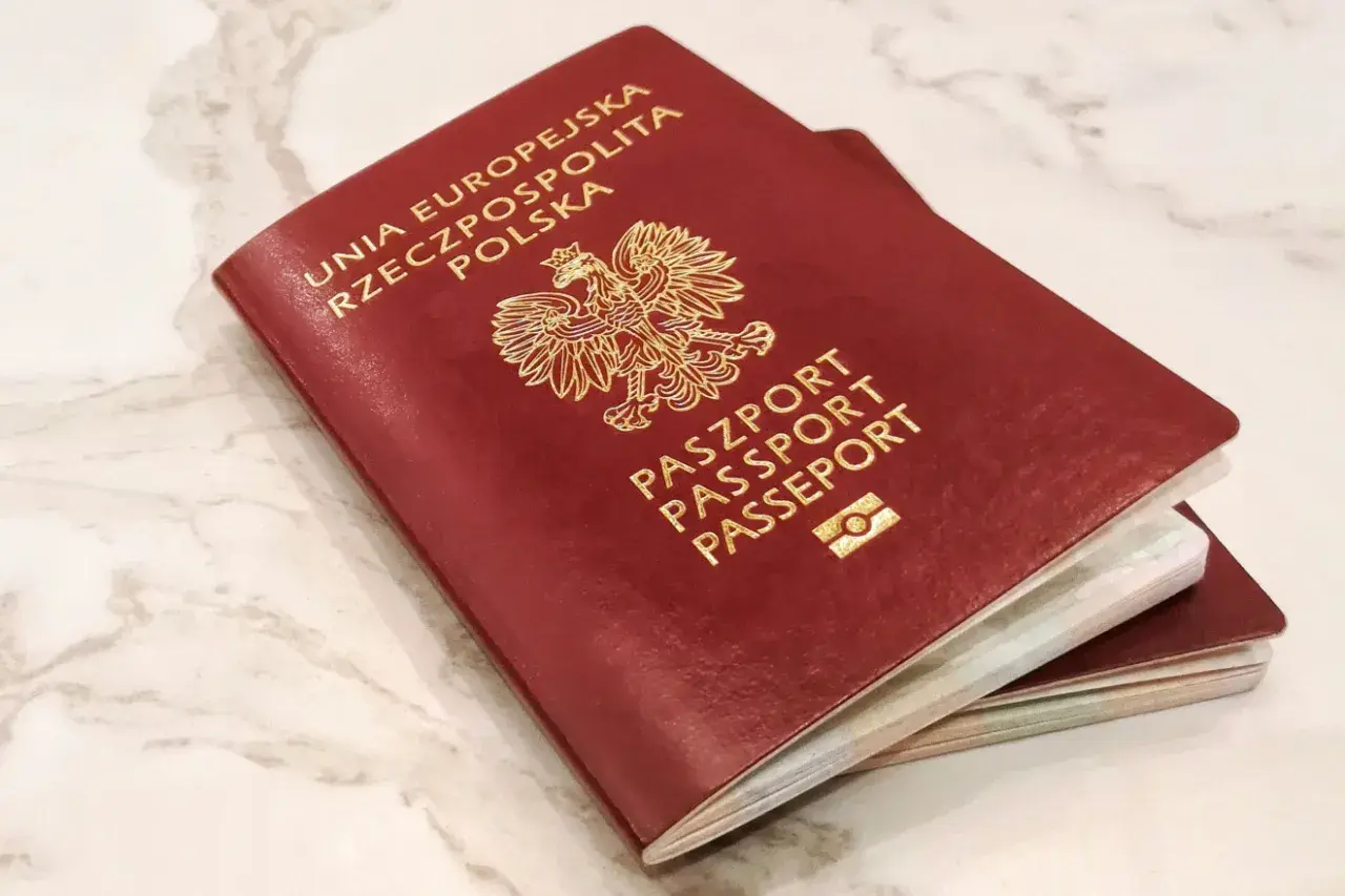 Dwa polskie paszporty, symbole wolności podróżowania i jedne z najsilniejszych paszportów na świecie, leżą na marmurowym blacie.