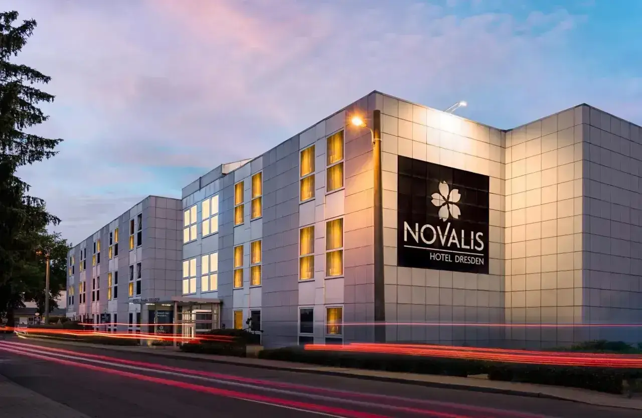 Novalis Hotel Dresden, z oświetlonymi oknami i neonowym znakiem, pokazuje, czym się różni hotel od motelu: oferuje więcej niż tylko nocleg.