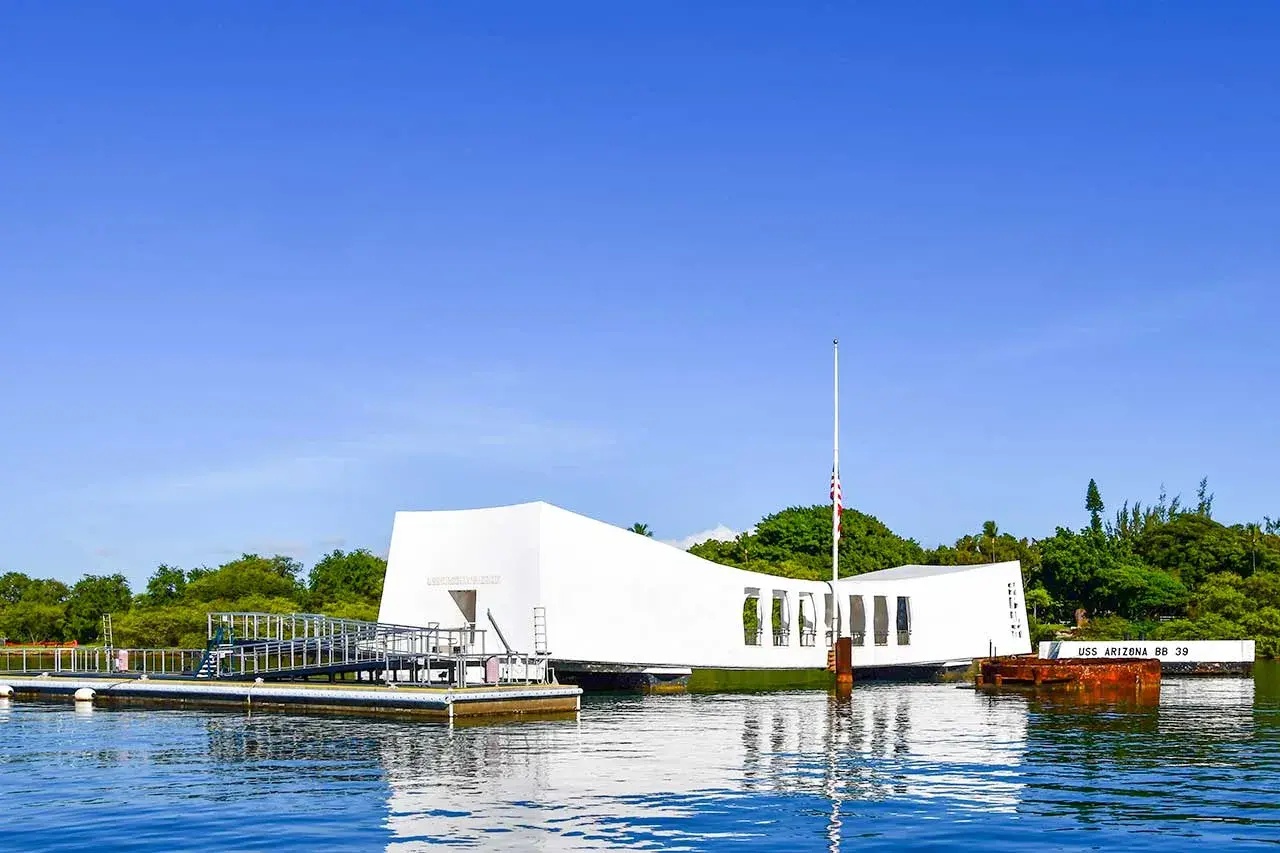 Pomnik USS Arizona w Pearl Harbor, biała konstrukcja nad wodą, upamiętnia tragiczne wydarzenia.