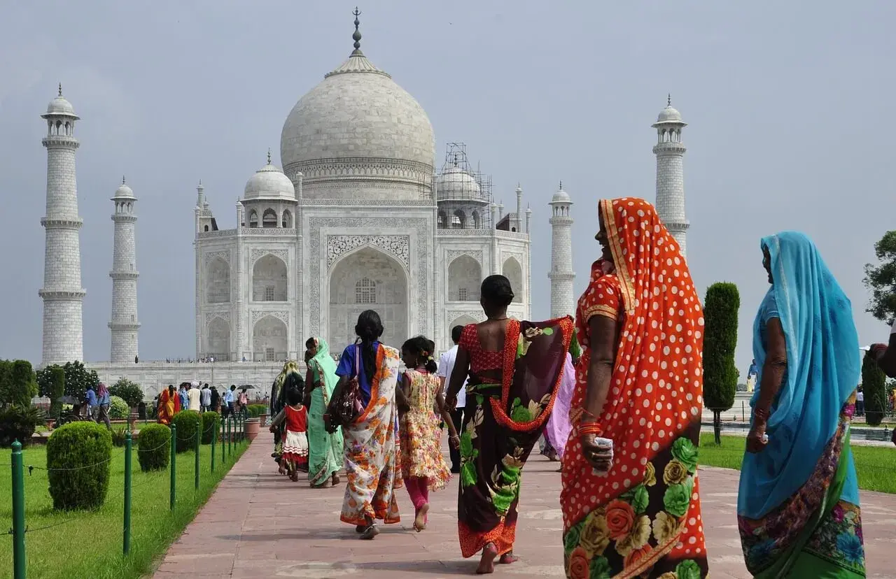 Kobiety w barwnych sari spacerują ścieżką ku Taj Mahal. Marzenie o podróży do Indii i uzyskaniu wizy do Indii staje się rzeczywistością.