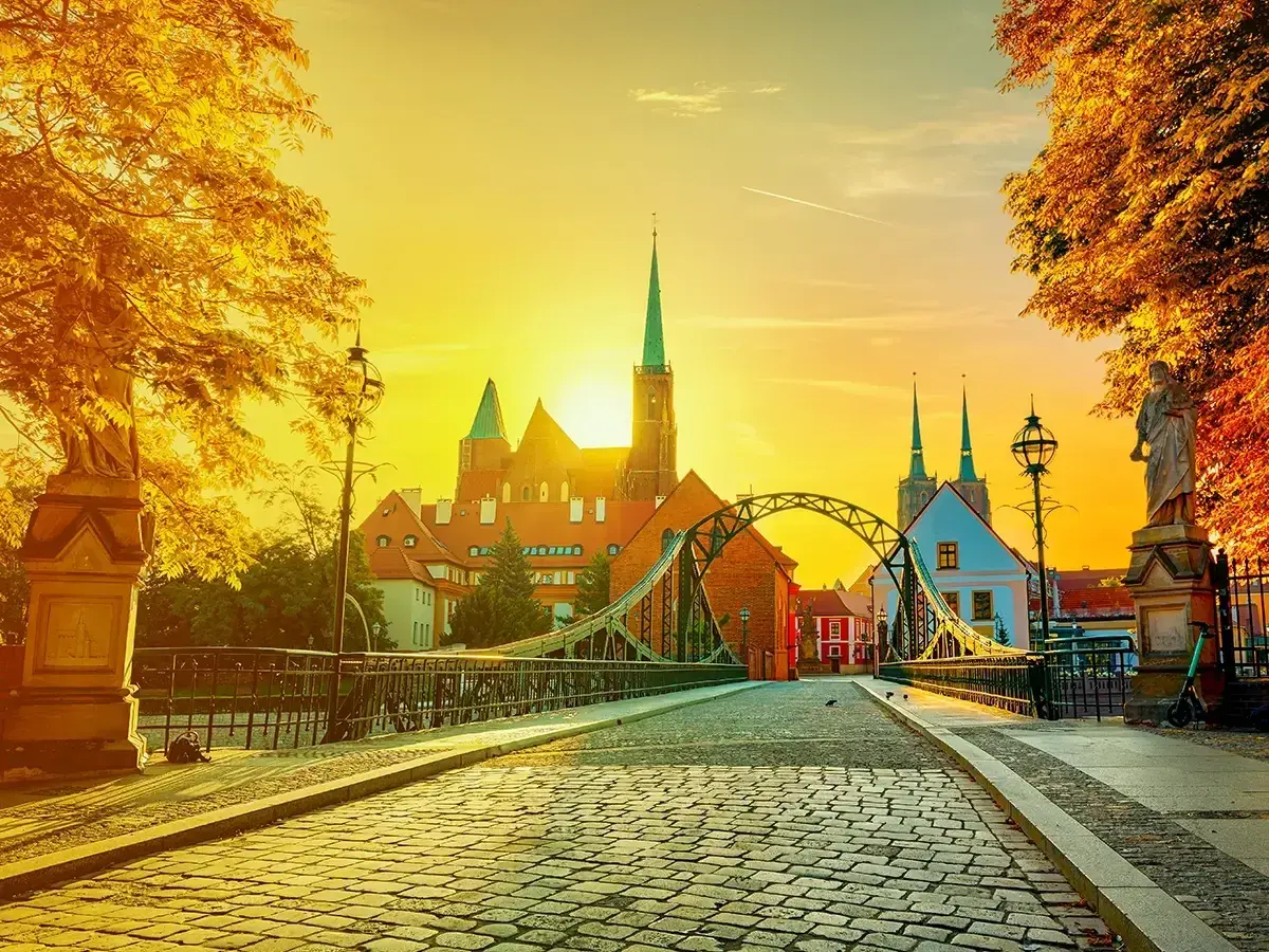 Zachód słońca nad Ostrowem Tumskim we Wrocławiu, idealny na city break z Wrocławia. Most Tumski i katedra w złotym blasku.