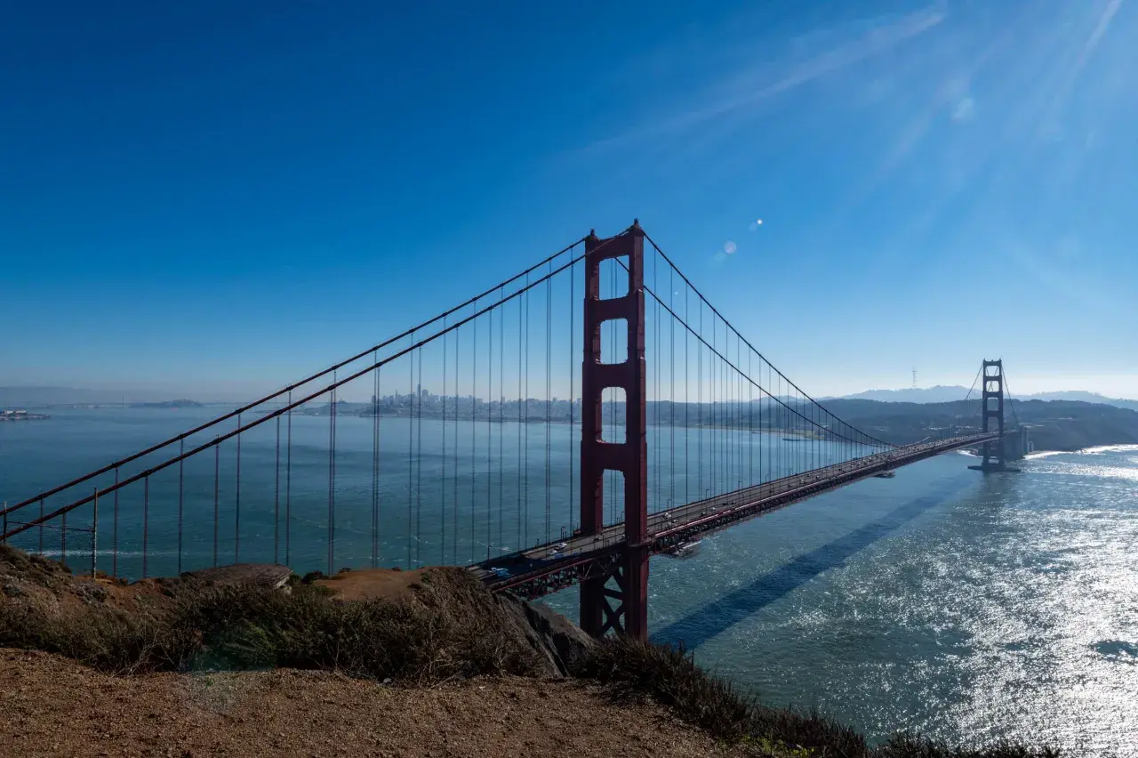 Ikoniczny most w San Francisco rozciąga się nad błękitną wodą, z panoramą miasta w oddali.