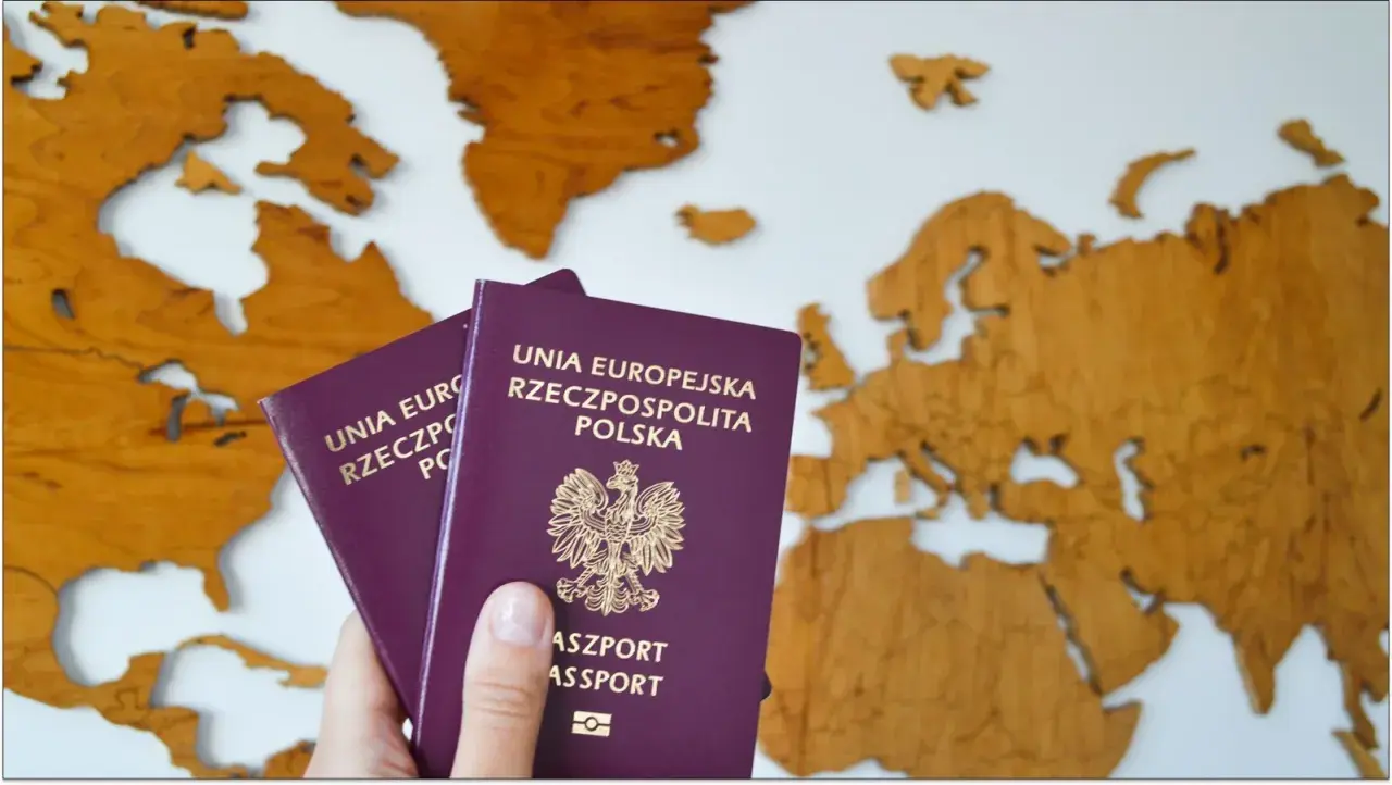 Dwa polskie paszporty, w tym paszport tymczasowy dla dziecka, na tle drewnianej mapy Europy.