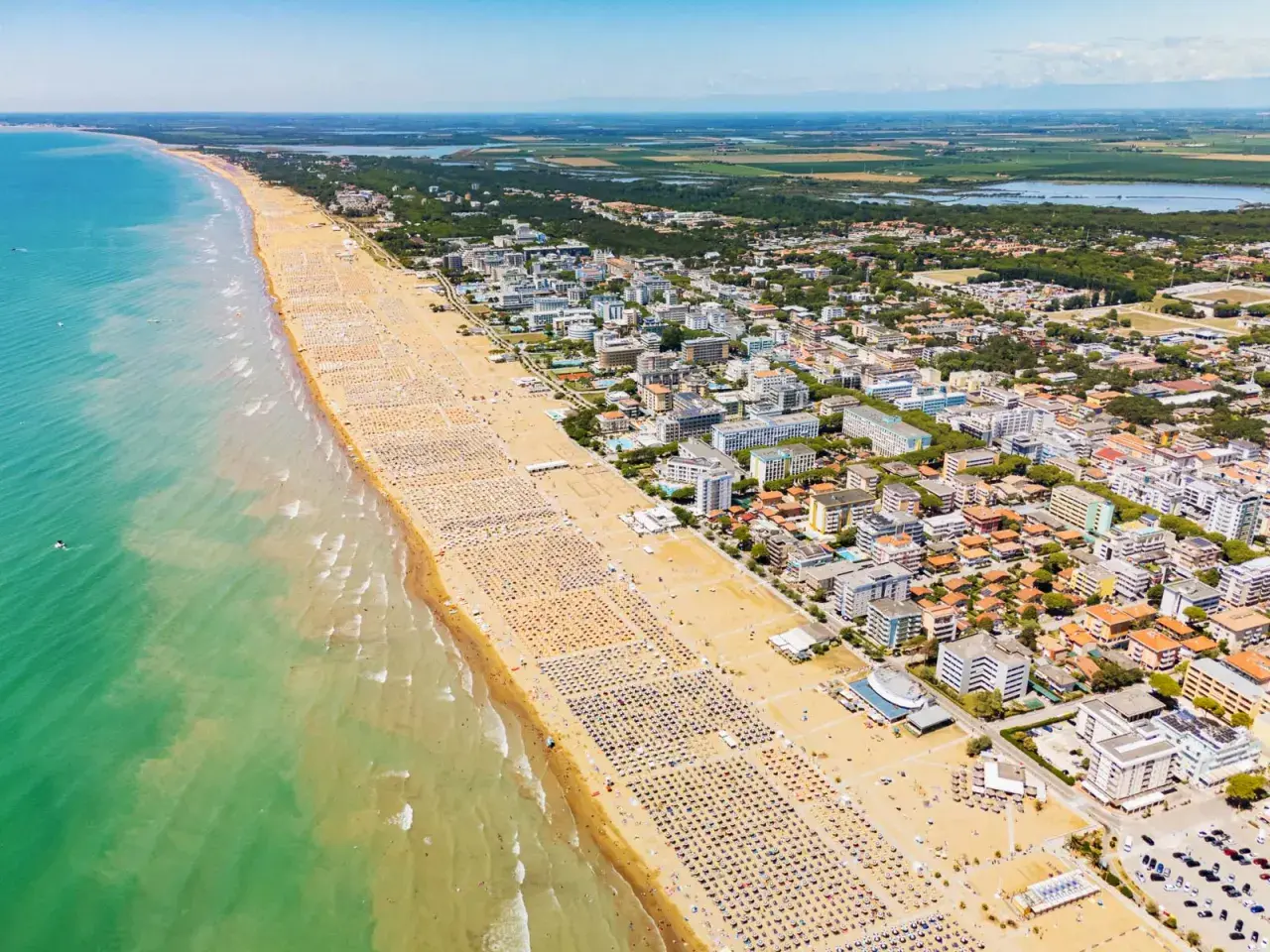 Słoneczna bibione plaża tętni życiem. Tysiące leżaków i parasoli tworzą barwny dywan, a turkusowe morze zaprasza do kąpieli.
