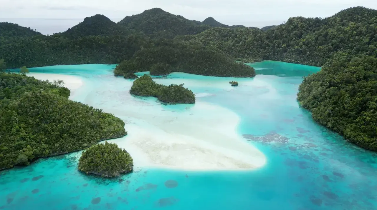 Rajskie krajobrazy Raja Ampat: turkusowa woda, białe plaże i bujna zieleń tropikalnych wysp.