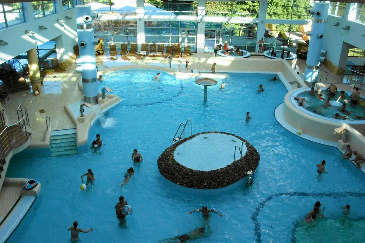 Wesoła atmosfera w aquaparku w Sopocie. Ludzie kąpią się w basenach, relaksują w jacuzzi. Wiele pozytywnych **aquapark sopot opinie** potwierdza, że to świetne miejsce na rodzinny wypoczynek.
