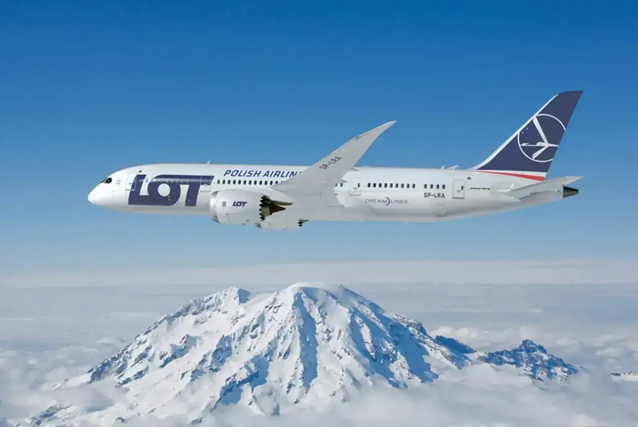 Samolot LOT Polish Airlines leci nad ośnieżonymi górami.